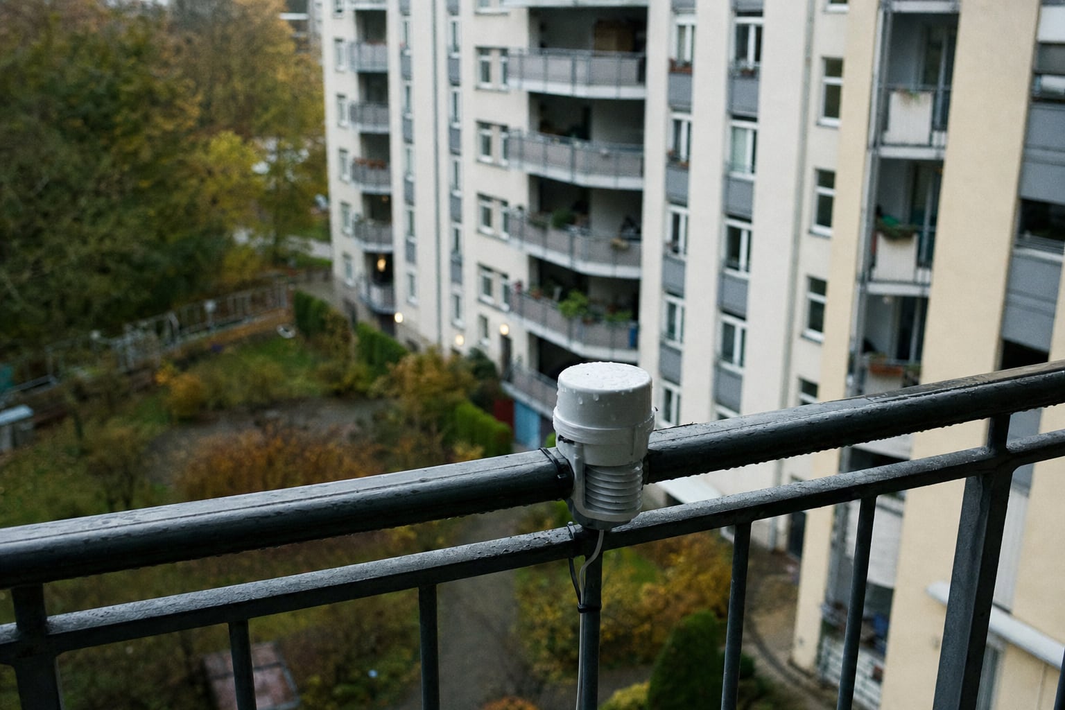 Kleiner Feinstaubsensor im Wettergehäuse an einem Balkongeländer