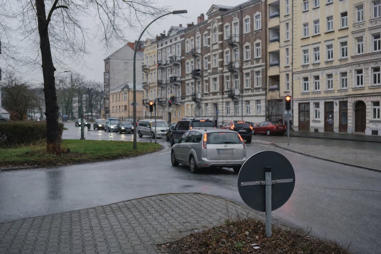 Stadteinfahrt mit Verkehr an einer Ampel bei bedecktem Himmel